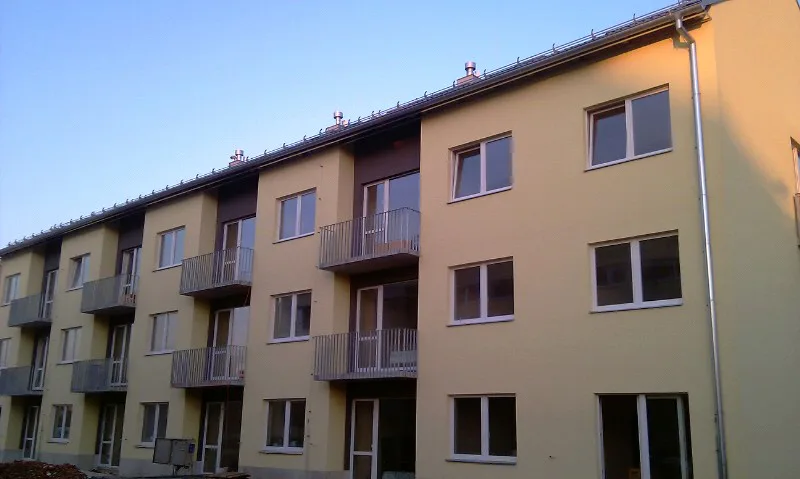 Bytový dům s balkony a novou žlutou fasádou